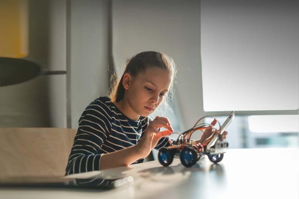 Young female student building a robotic car during an online technology class at 五大湖学习学院