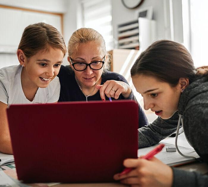 A mother is helping her two daughters with online classwork