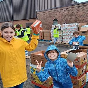 Image of Emberley, Lincoln, and Myles working at a food bank helping to unpack food. 
