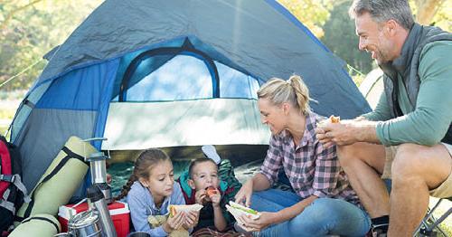 A family spending their national outdoor play days camping in a tent and having a picnic.